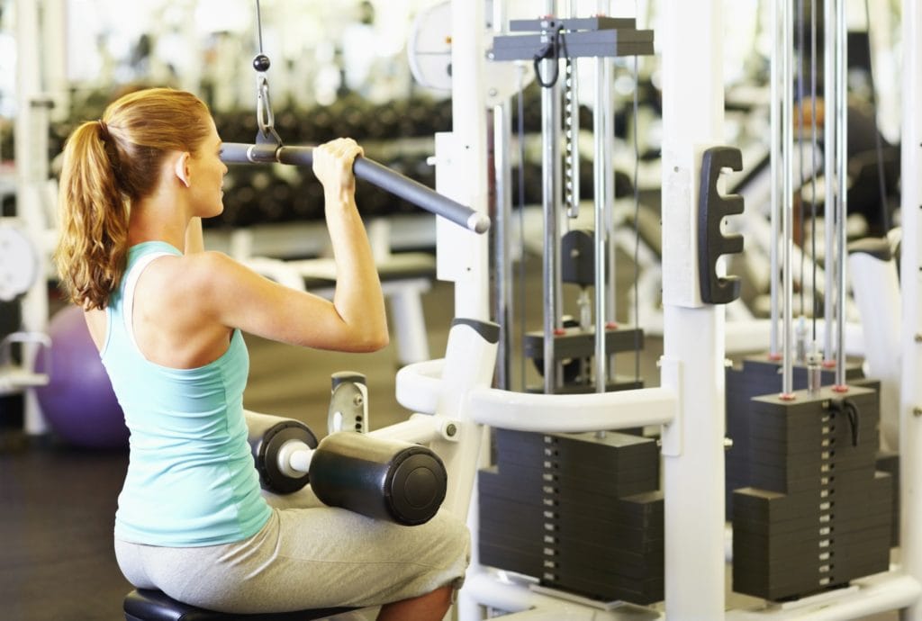 Portrait of young woman exercising on pulley at gym Arlberg